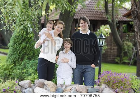 Young Beautiful Couple With Two Kids In A Garden