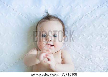 Sweet Little Baby On A White Blanket Playing With Its Hands