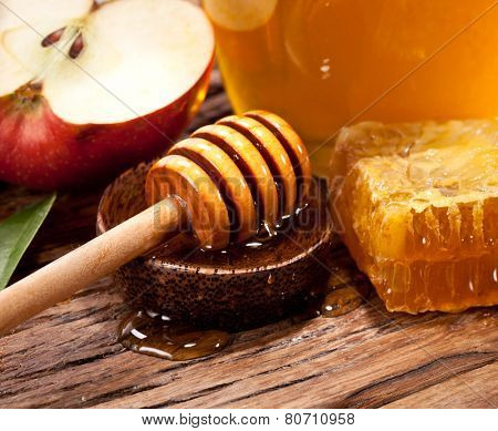 Honeycombs and wooden dripper. Can and apple on the background.