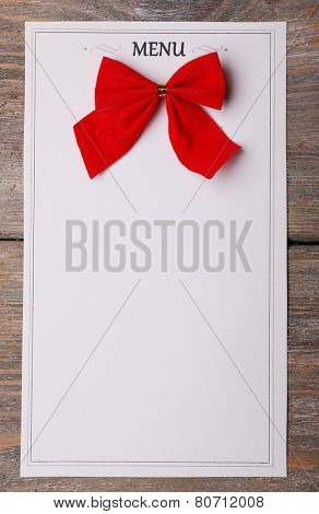 Menu sheet of paper with red bow on rustic wooden surface background