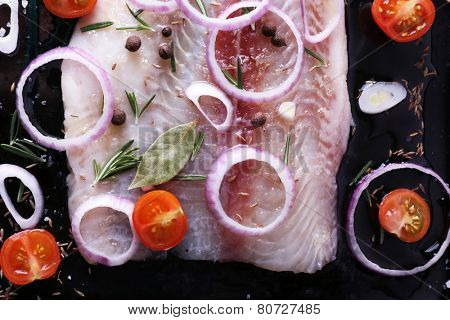 Pangasius fillet with spices and vegetables on firepan background