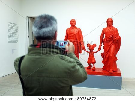 Visitor takes photo of the art work in a gallery