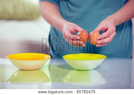 Female hands separating yolk and white of a cracked egg