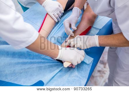 a group of doctors injections boy feet on medical table