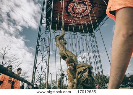 Team helping woman to climbing rope in a test of obstacle race