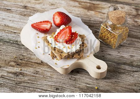 Crispy bread for breakfast for a healthy diet with curd cheese, strawberry, flower bee pollen on a wooden cutting board easy. concept of healthy family nutrition. selective Focus