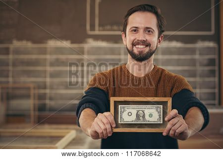 Entrepreneur showing framed bank note with a proud smile