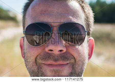 Man Taking A Picture Of Himself And Woman Reflecing In Singlasses.