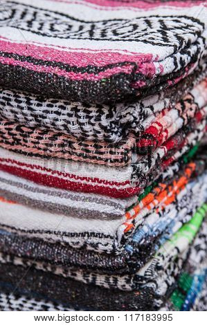 Colorful Mexican serapes hang in row.