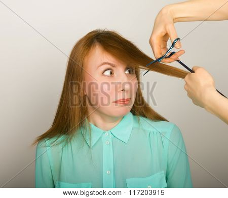 Beautiful young red-haired girl at the hairdresser makes blow drying, shorn bangs, hair polishing