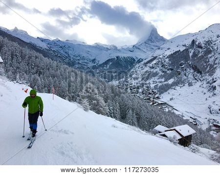 Man asceding on touring skis at beautiful winter landscape with fresh snow. Switzerland Alps, Zermatt, Materhorn mountain in background