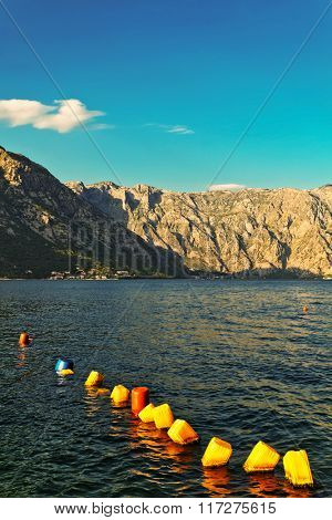 Line of colorful buoys, made of jerrican, mountains in the background