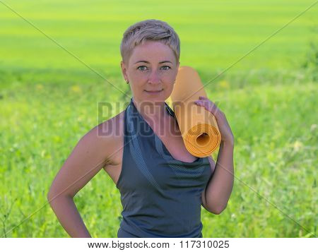 Mature Woman Holding Rolled Up Exercise Mat Outdoors