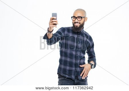 Cheerful baldheaded young african american man with beard in glasses smiling and taking selfie
