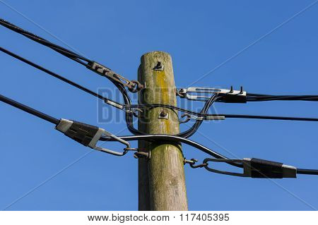 wooden electricity post against blue sky