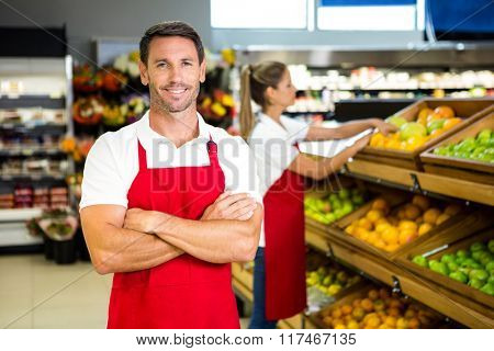 Smiling worker in front of colleague in grocery store