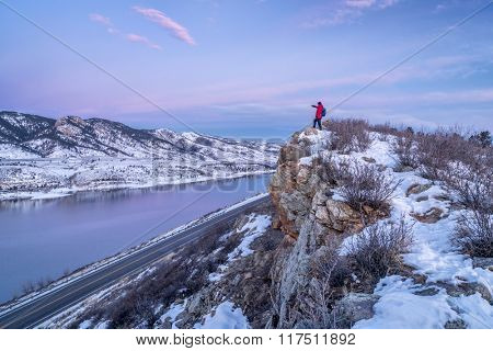 hiking Colorado before sunrise - male hiker on cliff above Horsetooth Reservoir in winter scenery