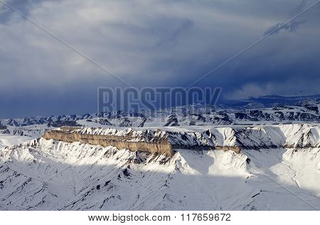 Winter Mountains At Sun Evening And Gray Storm Clouds