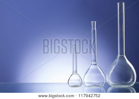 Assorted empty laboratory glassware, test-tubes. Blue tone medical background. Copy space for text.