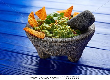Guacamole with nachos avocado in Mexican molcajete on blue wood table