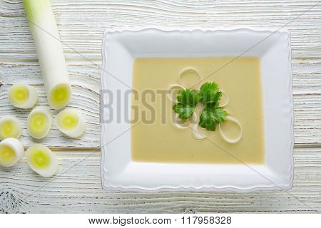 vichyssoise cream soup with leeks on white wood table
