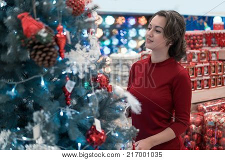 View from behind. Cheerful happy customer girl choosing Christmas tree for the new year on Christmas Eve. difficult decision. Various choice