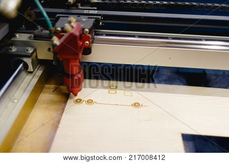 The automatic machine burns the lower line on the workpiece with the laser. There is a smoke from work. Top view at an angle close up