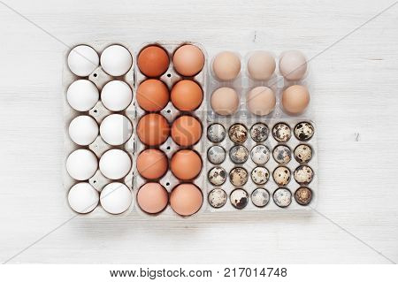 Some types of eggs in the packages on the white wooden table