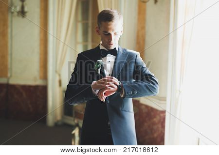 Happy handsome smiling groom posing with boutonniere.