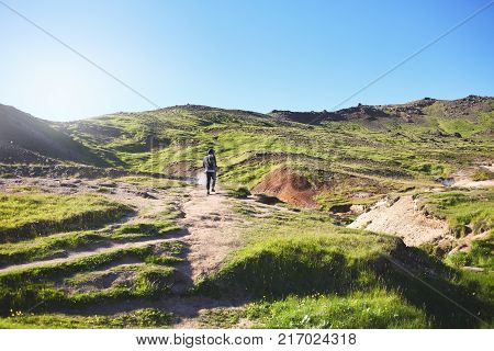 back view of man traveler on a walk in the Valley of the river of Hveragerdi Iceland. Hiking Tour of Reykjadalur Hot Springs