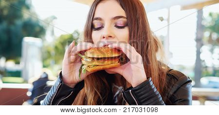 Portrait of a teenage girl eating a hamburger