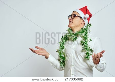man with green tinsel on his neck looking at free space for copying, bright background, new year.