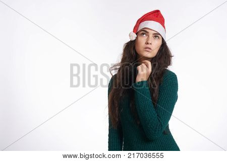 woman holding her hand near the chin and looking up, light background, free space for copy, christmas.