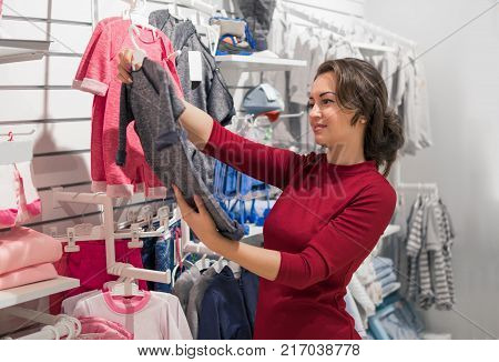 Shopping young woman buys children's wear in the shop. Wide choice