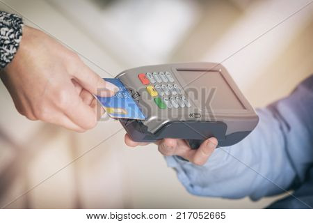 Paying with credit or debit card in wireless payment terminal at shop