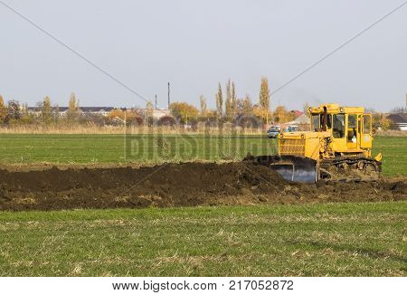 The Yellow Tractor With Attached Grederom Makes Ground Leveling.