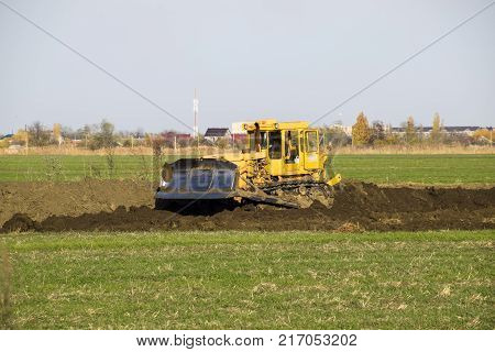 The Yellow Tractor With Attached Grederom Makes Ground Leveling.