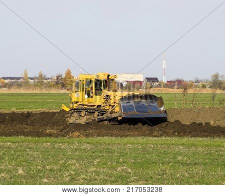 The Yellow Tractor With Attached Grederom Makes Ground Leveling.