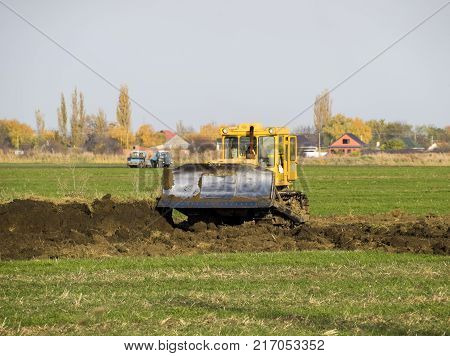 The Yellow Tractor With Attached Grederom Makes Ground Leveling.