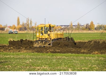 The Yellow Tractor With Attached Grederom Makes Ground Leveling.