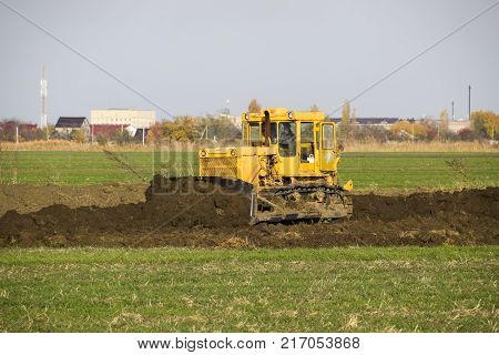 The Yellow Tractor With Attached Grederom Makes Ground Leveling.