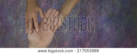Your Palms are a map of your past and future life - female palm reader holding a male hand examining the lines and bumps against a flower of life rustic stone background