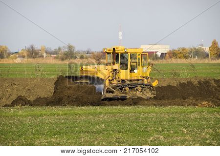 The Yellow Tractor With Attached Grederom Makes Ground Leveling.