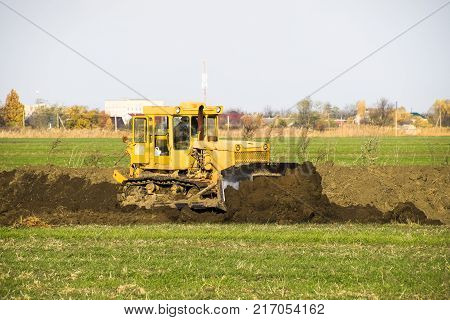 The Yellow Tractor With Attached Grederom Makes Ground Leveling.