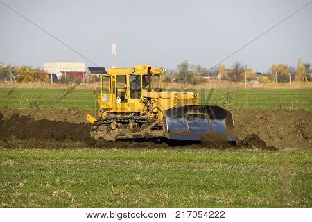 The Yellow Tractor With Attached Grederom Makes Ground Leveling.