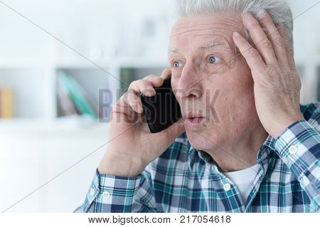 Portrait of senior man with phonel at home