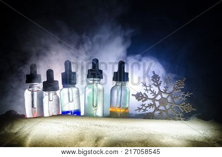 Electronic Cigarette With Vape Liquids And Christmas Decorations On Bokeh Lights Background