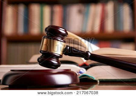 Law gavel or judge mallet on a wooden desk, law books background. Education and legal law concept