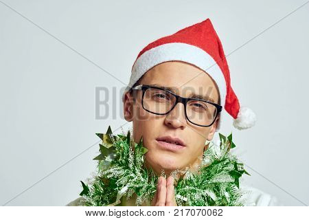 man in glasses with green tinsel around his neck, portrait, new year, light background.