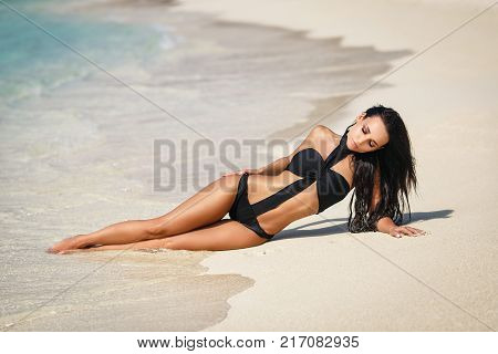 Beautiful young girl in a sexy black swimsuit in paradise islands